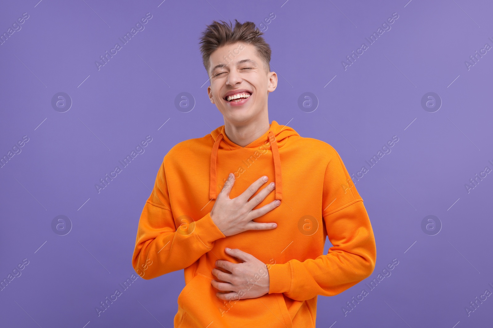 Photo of Portrait of young man laughing on violet background