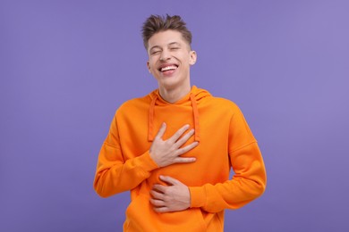 Photo of Portrait of young man laughing on violet background