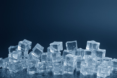 Photo of Crystal clear ice cubes with water drops against black background