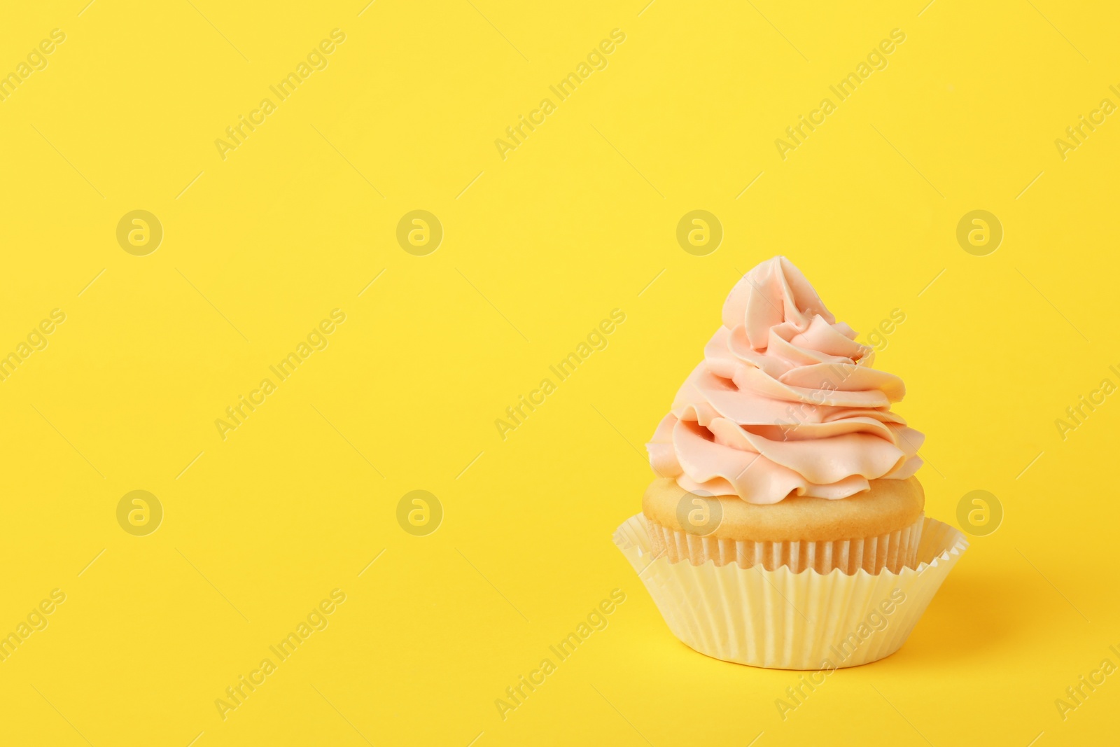 Photo of Tasty cupcake with cream on yellow background, space for text