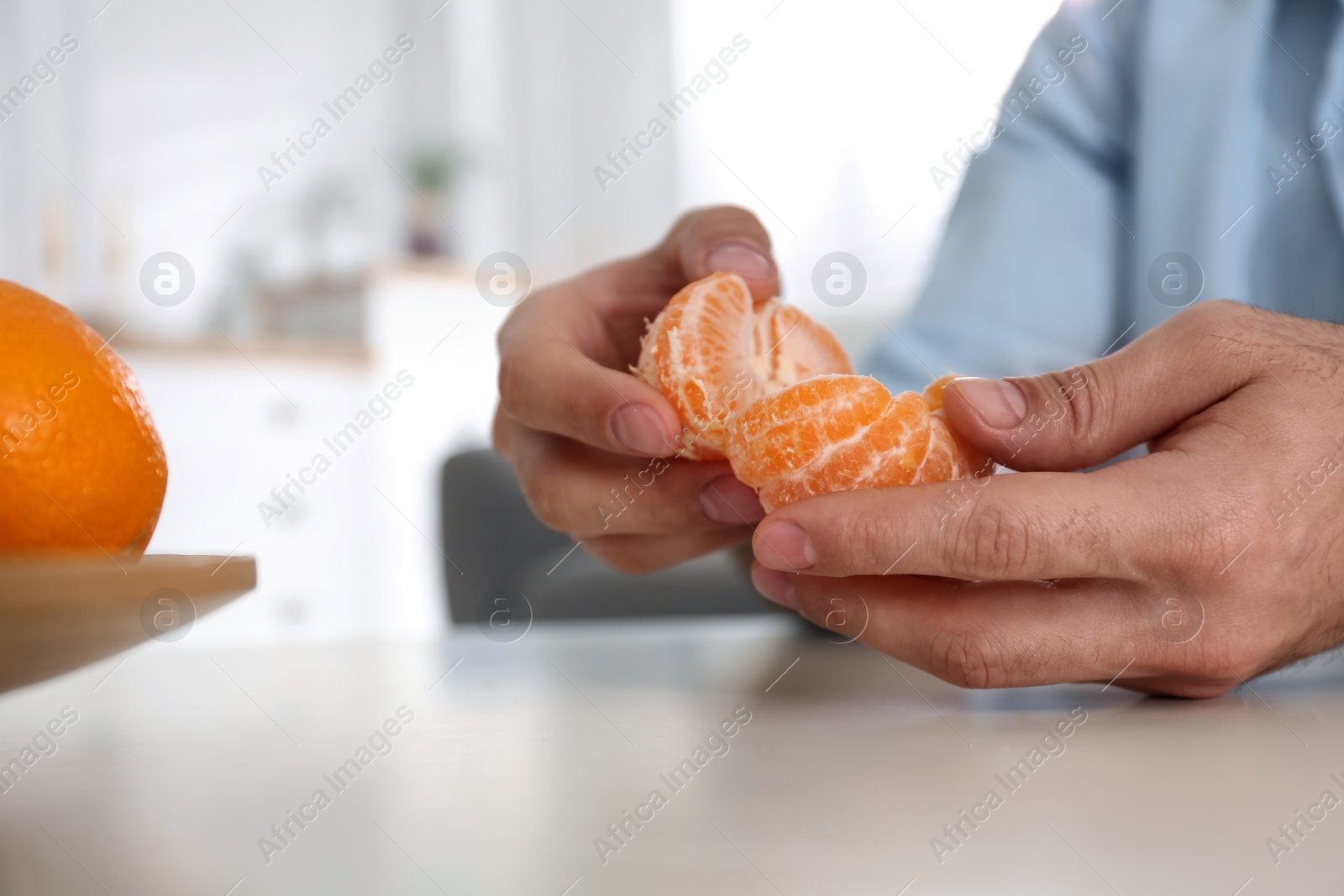 Photo of Man with fresh tangerine at table indoors, closeup