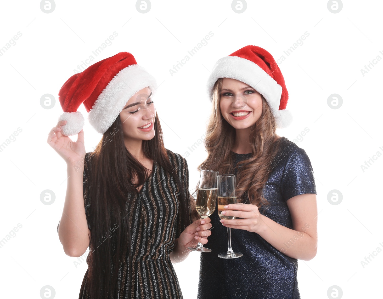 Photo of Beautiful young women in Santa hats with glasses of champagne on white background. Christmas celebration