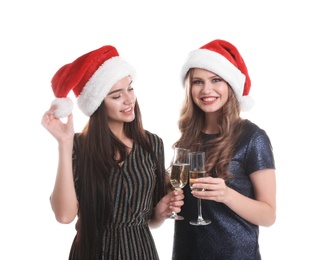 Beautiful young women in Santa hats with glasses of champagne on white background. Christmas celebration