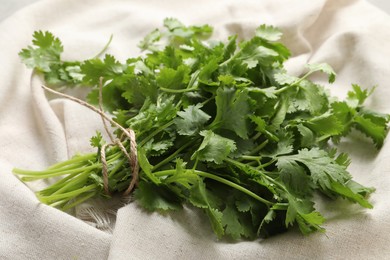 Bunch of fresh green cilantro with twine on white fabric, closeup