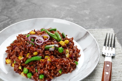 Photo of Plate of boiled brown rice with vegetables on table, closeup. Space for text