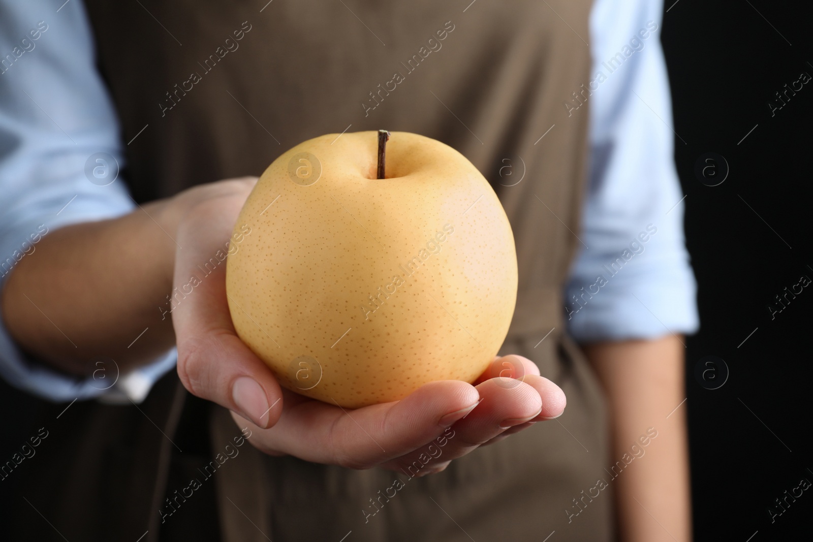 Photo of Woman holding ripe apple pear on black background, closeup