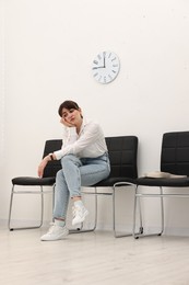 Woman sitting on chair and waiting for appointment indoors