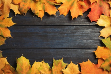 Frame made of autumn leaves on wooden background, top view with space for text