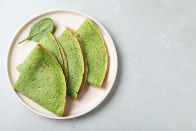 Tasty spinach crepes on light grey marble table, top view. Space for text