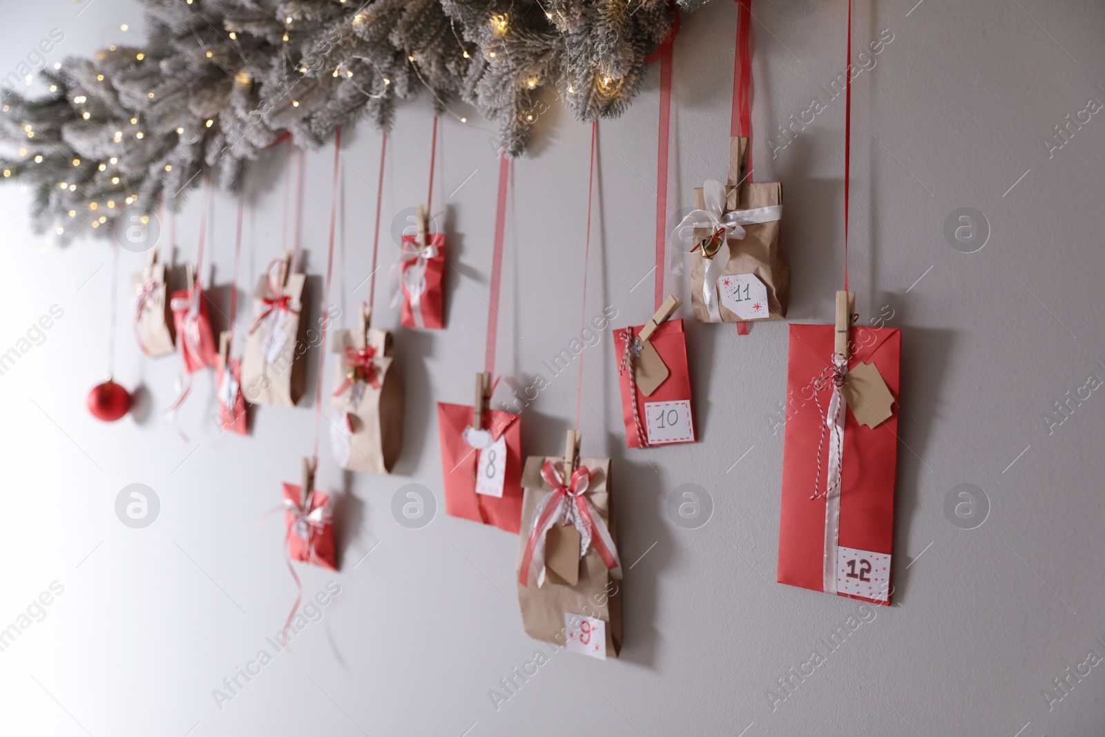 Photo of Christmas advent calendar with decorative fir branches and fairy lights hanging on wall