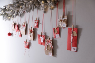 Photo of Christmas advent calendar with decorative fir branches and fairy lights hanging on wall