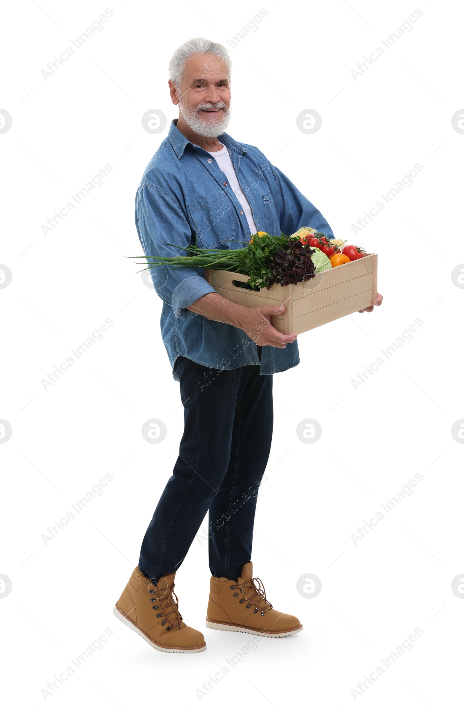 Photo of Harvesting season. Happy farmer holding wooden crate with vegetables on white background