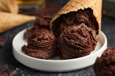 Tasty ice cream scoops and waffle cones on dark textured table, closeup