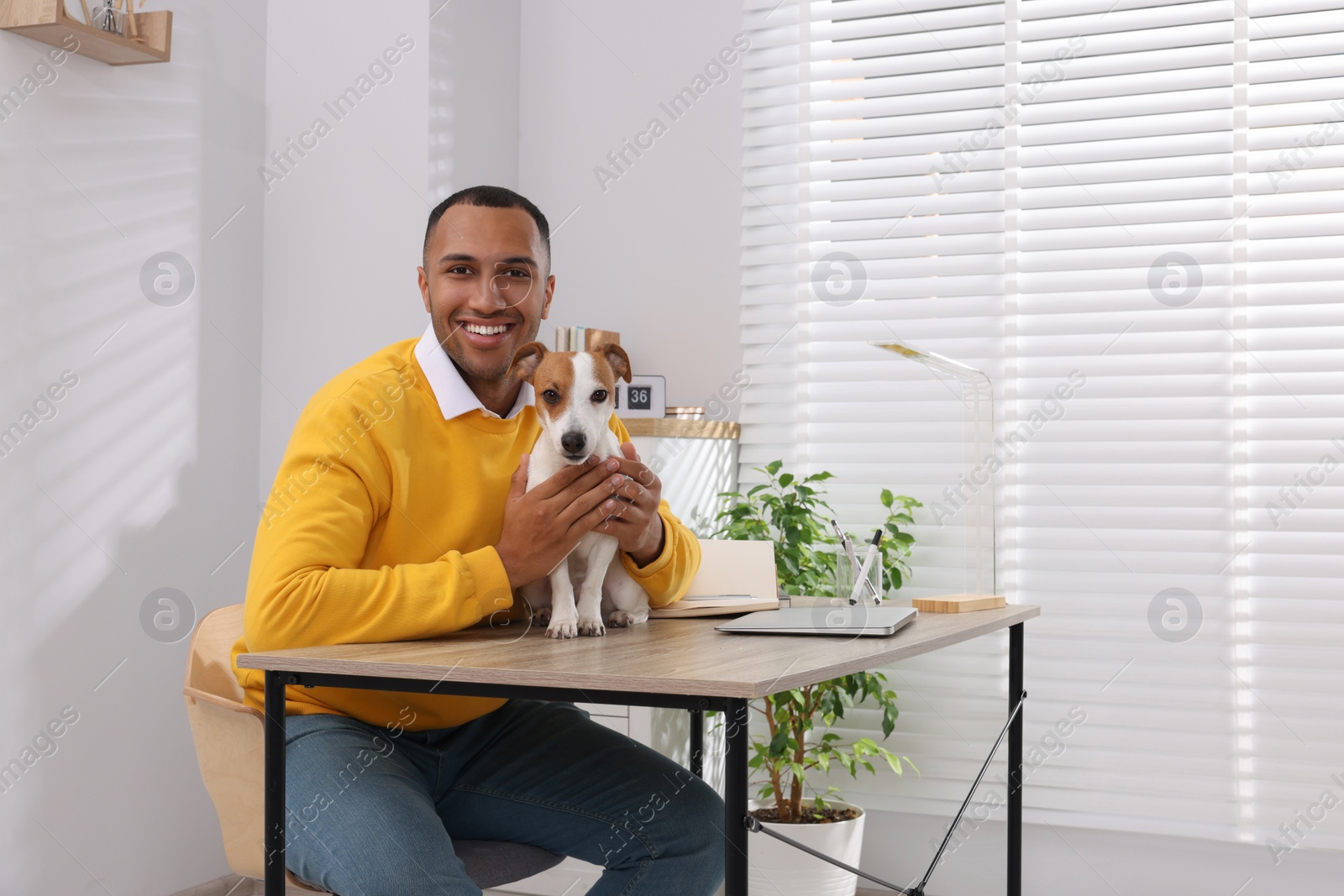 Photo of Young man with Jack Russell Terrier at desk in home office