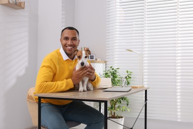 Photo of Young man with Jack Russell Terrier at desk in home office