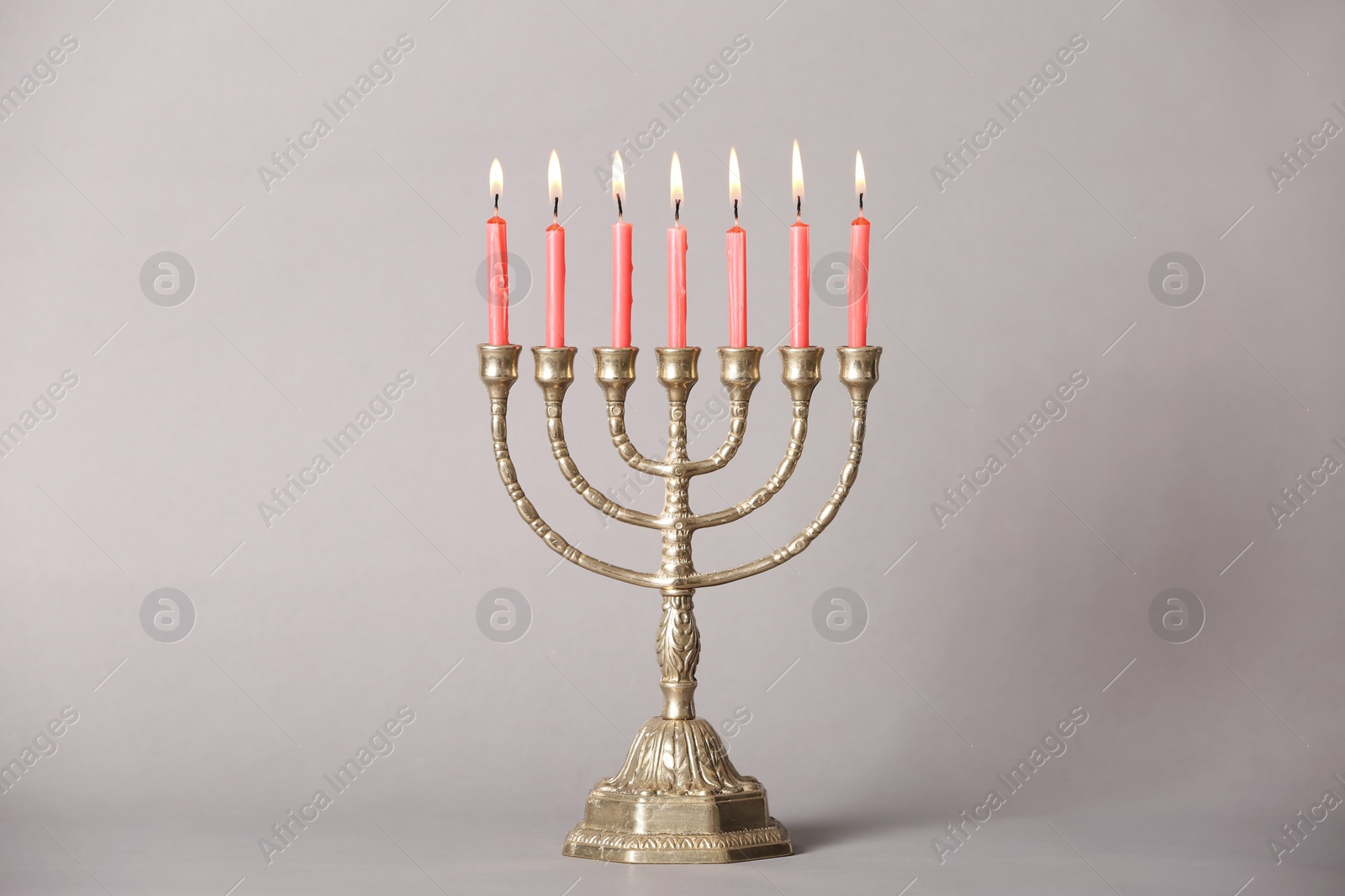 Photo of Golden menorah with burning candles on light grey background