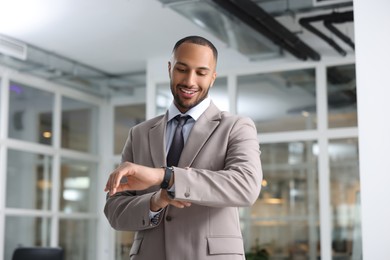 Photo of Happy man looking at his watch in office. Lawyer, businessman, accountant or manager