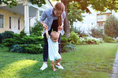 Teen nanny with cute baby on green grass outdoors