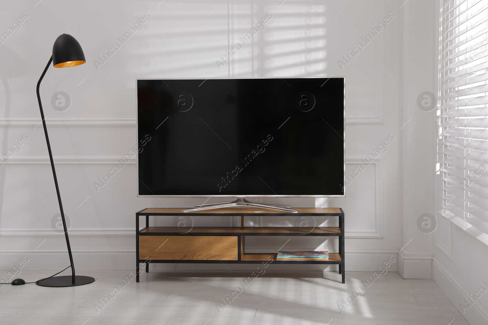 Photo of Modern TV on stand near white wall indoors. Interior design
