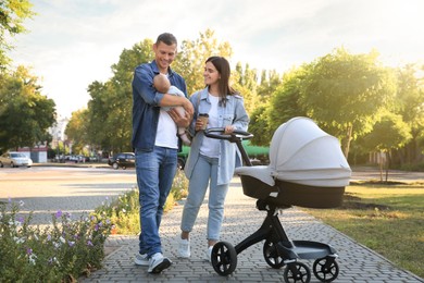 Photo of Happy parents walking with their baby in park on sunny day