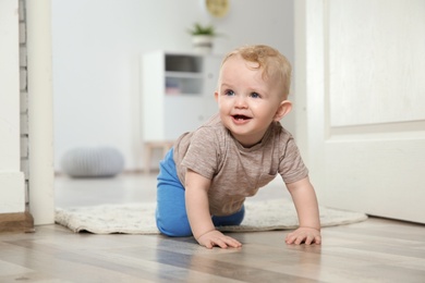 Cute little baby crawling on floor indoors