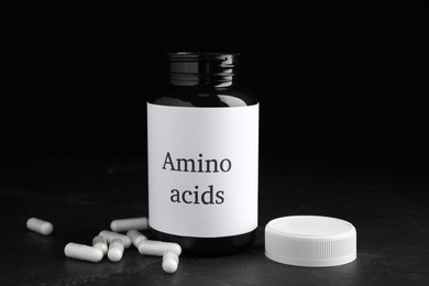 Photo of Amino acid pills and jar on black table