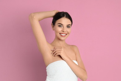 Photo of Young woman showing hairless armpit after epilation procedure on pink background
