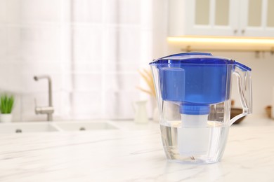 Water filter jug on white marble table in kitchen, space for text