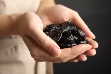 Photo of Woman holding handful of dried plums, closeup. Healthy fruit