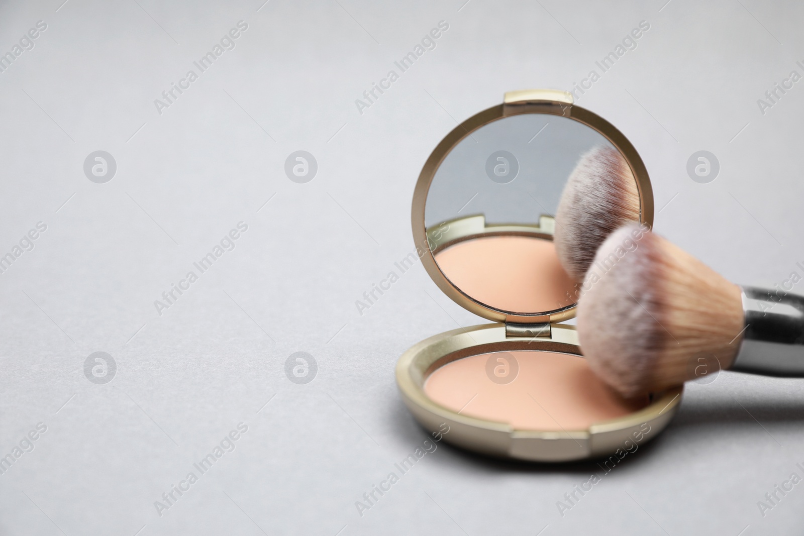 Photo of Face powder and brush on light grey background, closeup. Space for text