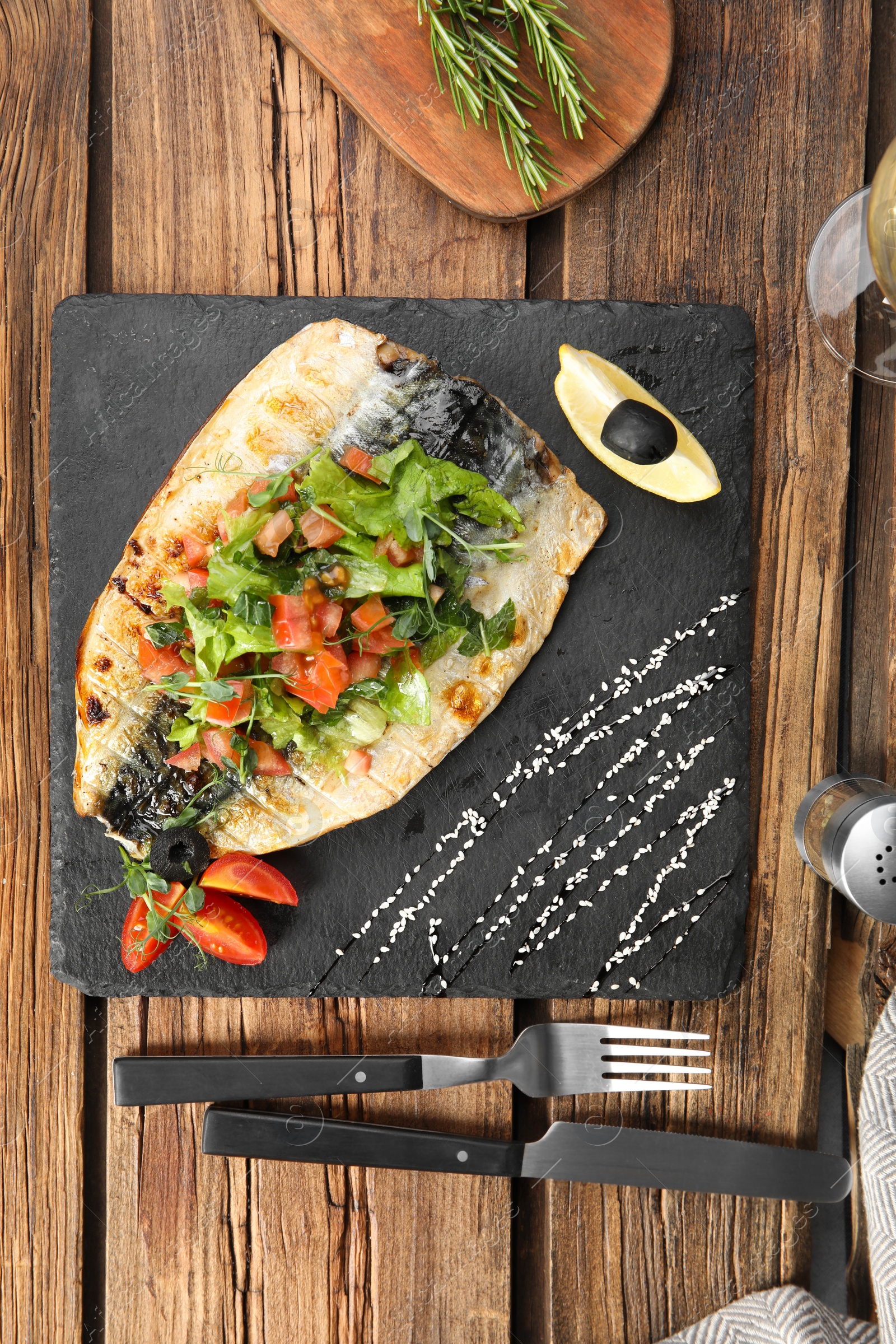 Photo of Delicious grilled fish served on wooden table, flat lay