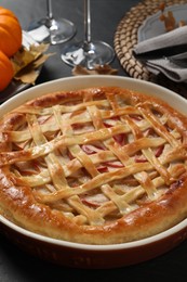 Photo of Delicious homemade apple pie and autumn decor on black table, closeup. Thanksgiving Day celebration