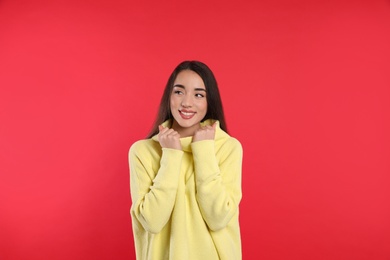 Photo of Beautiful young woman wearing yellow warm sweater on red background