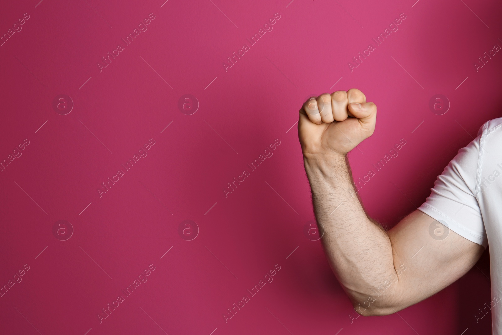 Photo of Young man showing clenched fist on color background. Space for text