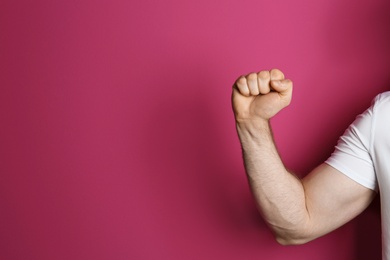 Young man showing clenched fist on color background. Space for text