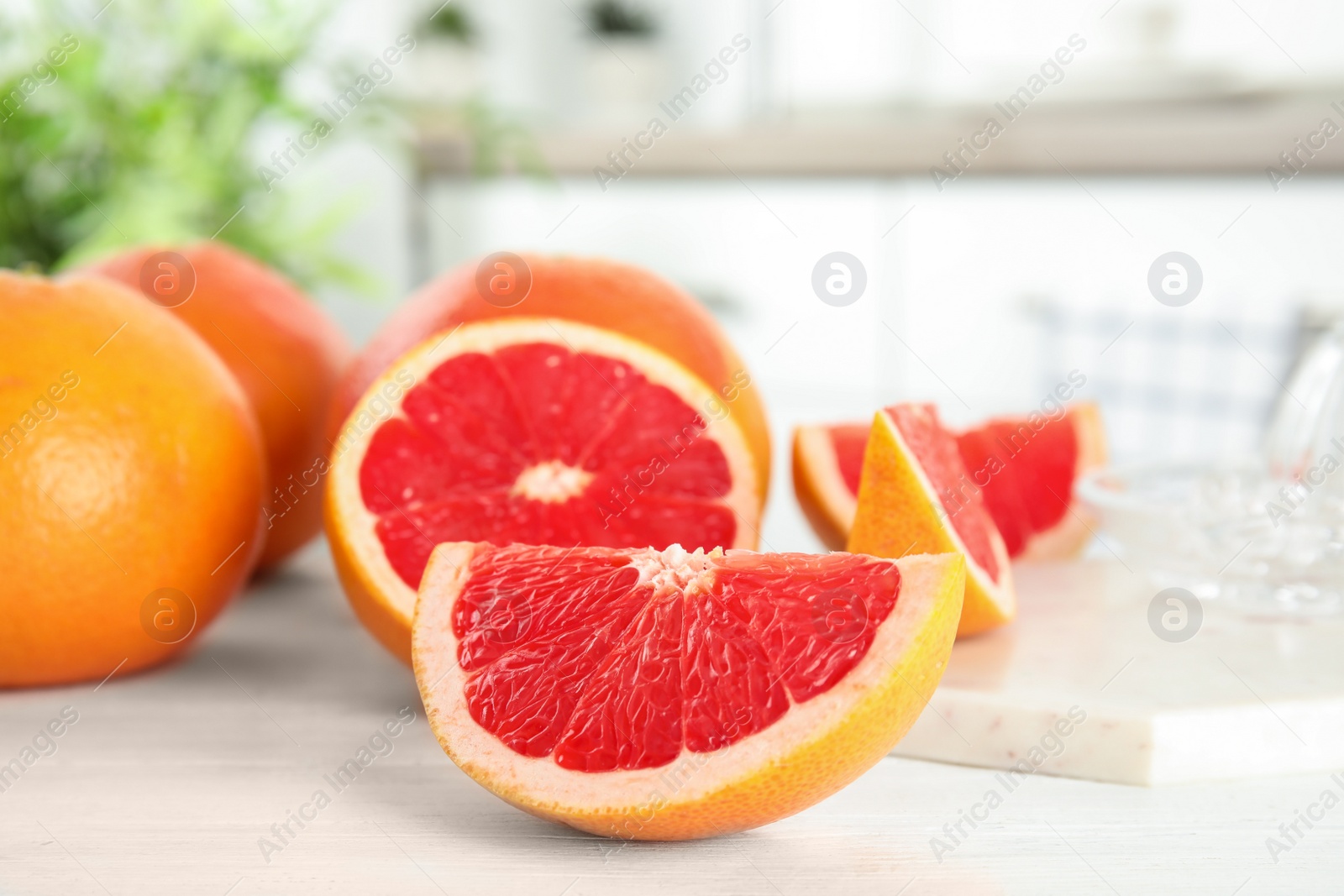 Photo of Cut and whole grapefruits on table against blurred background