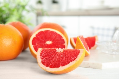 Cut and whole grapefruits on table against blurred background