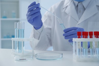 Photo of Scientist dripping sample into test tube in laboratory, closeup. Medical research