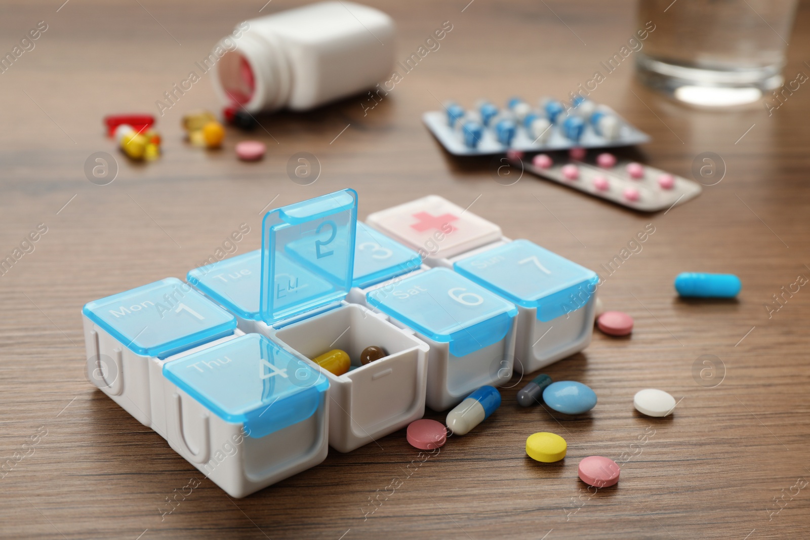 Photo of Plastic box with different pills on wooden table