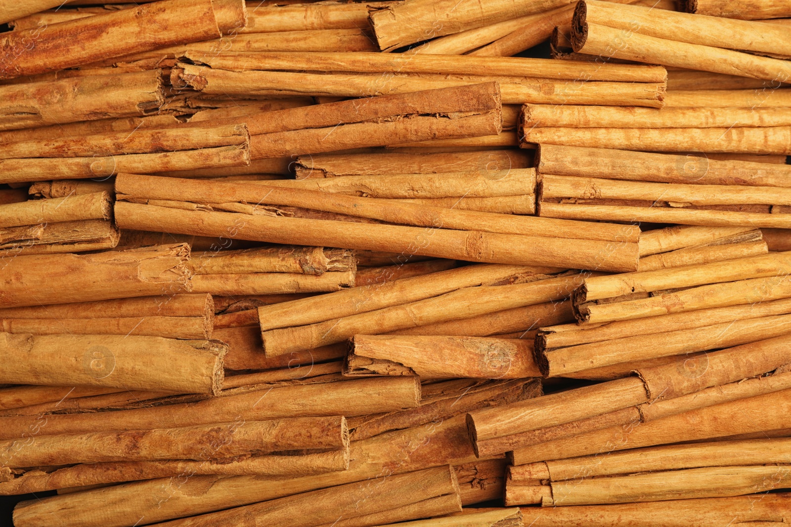 Photo of Aromatic dry cinnamon sticks as background, closeup