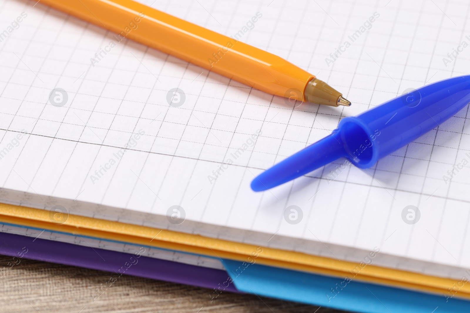 Photo of Ballpoint pen and notebook on wooden table, closeup