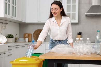 Smiling woman separating garbage in kitchen, low angle view
