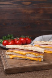 Photo of Delicious grilled sandwiches with ham and cheese on wooden table