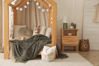 Photo of Stylish child room interior with wooden house bed