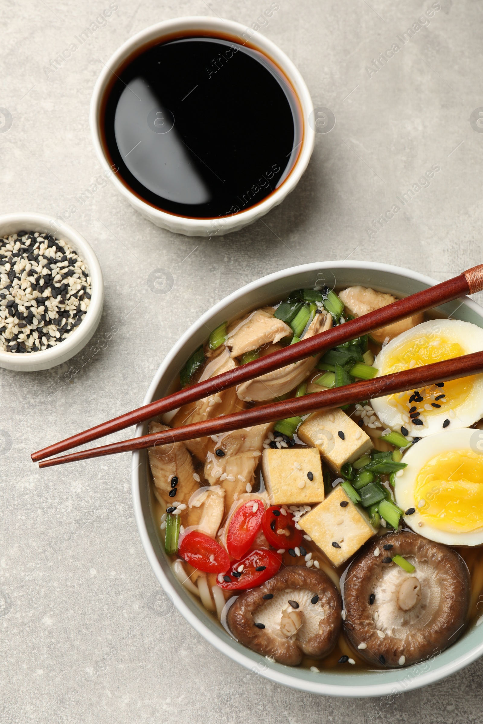 Photo of Delicious ramen served on grey table, flat lay. Noodle soup