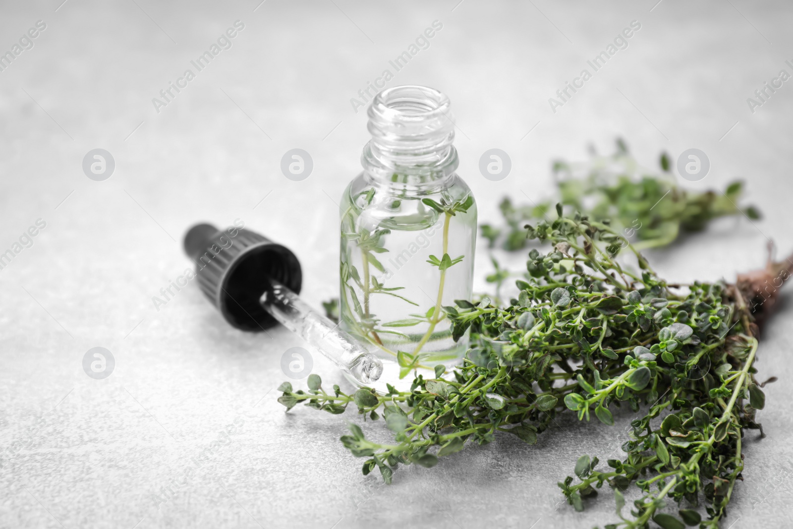 Photo of Thyme essential oil on light grey table