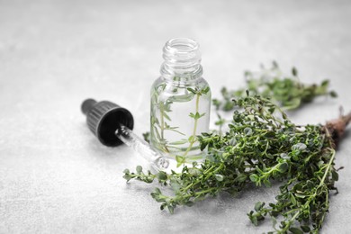 Photo of Thyme essential oil on light grey table
