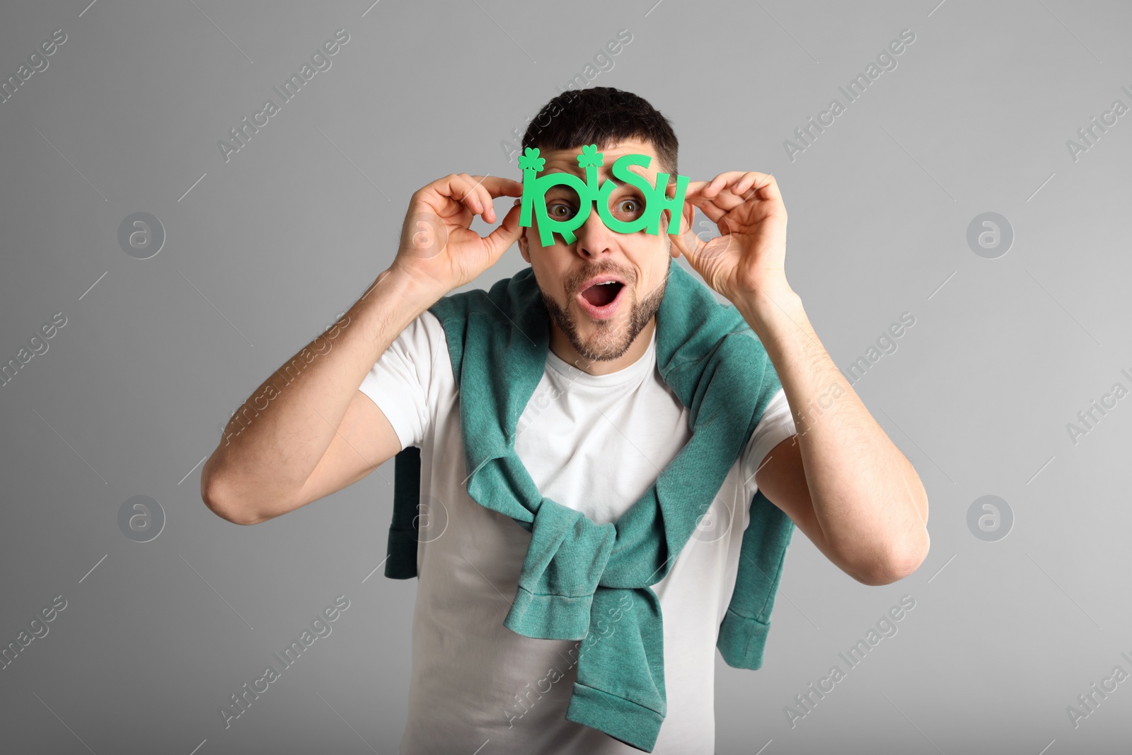 Photo of Emotional man in St Patrick's Day outfit on light grey background