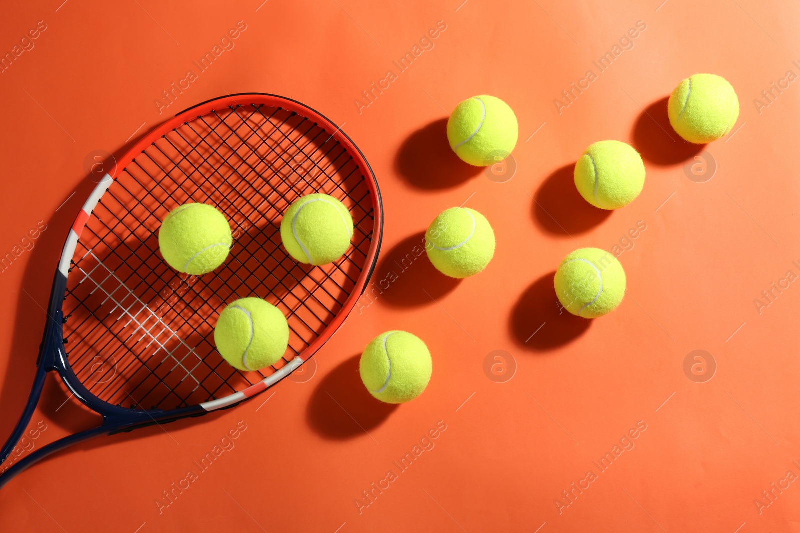 Photo of Tennis racket and balls on orange background, flat lay. Sports equipment