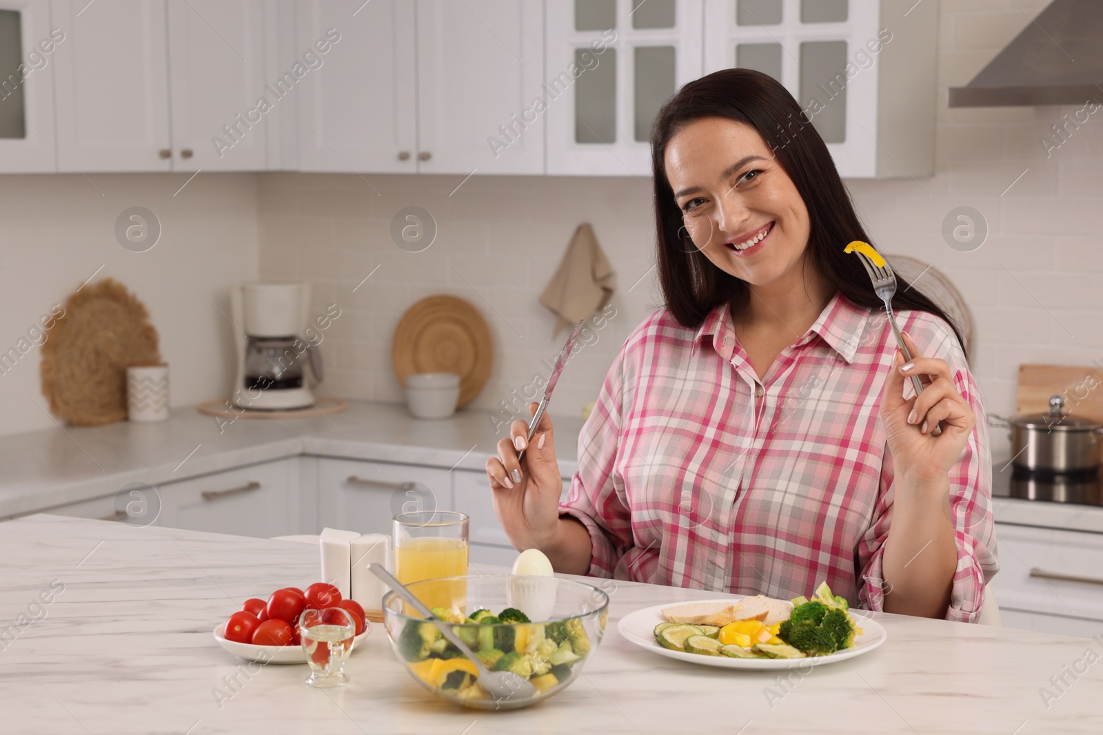 Photo of Beautiful overweight woman having healthy meal at table in kitchen